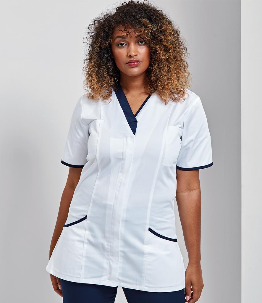 A woman wearing white healthcare workwear, standing against a plain background.