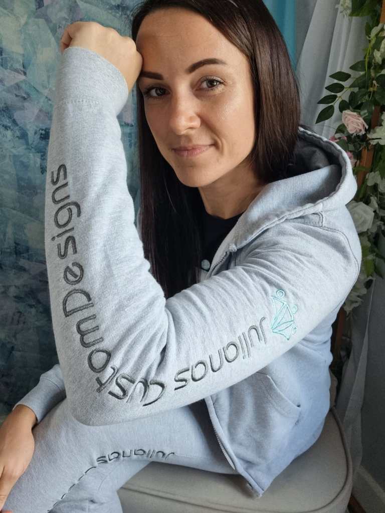 An image showcasing the logo embroidery on the sleeve of a grey zoodie.