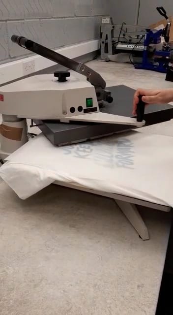 Demonstrating the heat pressing process for applying artwork onto fabric, with personalisation options available.