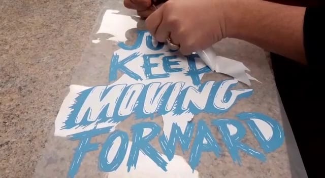 Peeling the artwork off the printed sheet for heat pressing, with personalisation options.